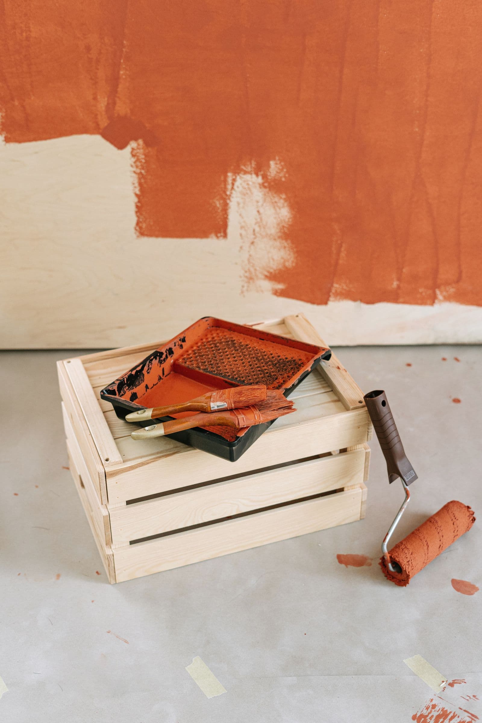 Painting materials and tools arranged on a wooden crate at a job site