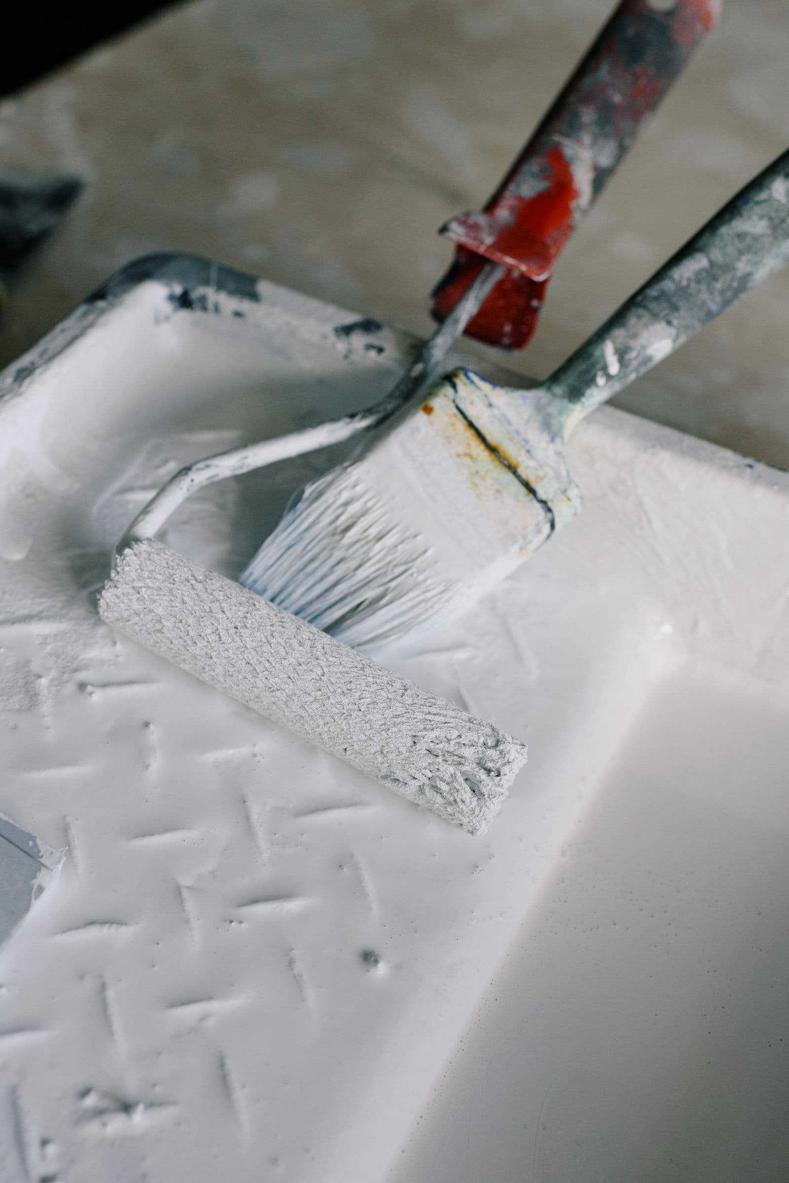 Close-up detail of a paint roller and brush resting on a tray, ready for a precise finish