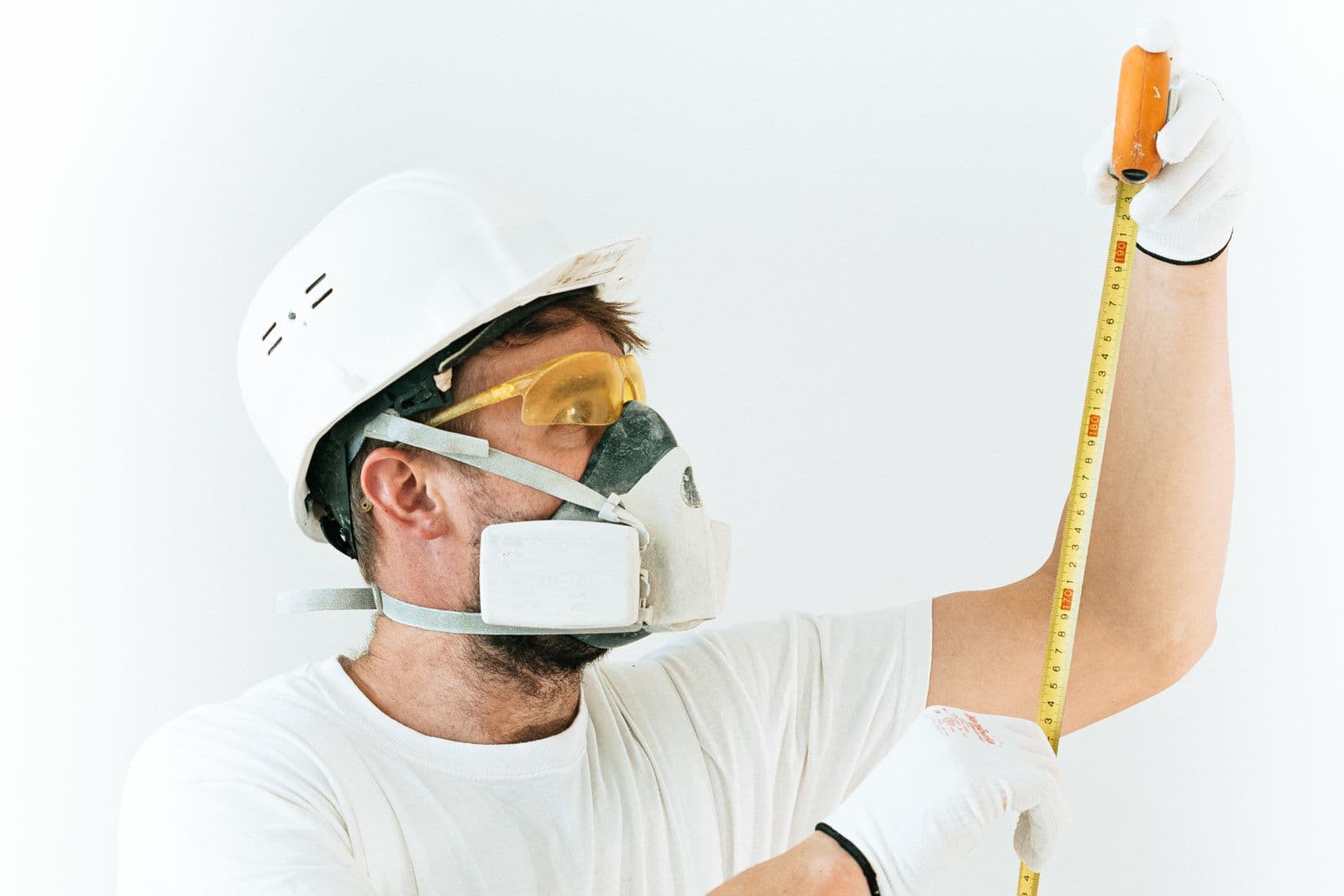 A craftsman carefully measuring a wall before beginning work
