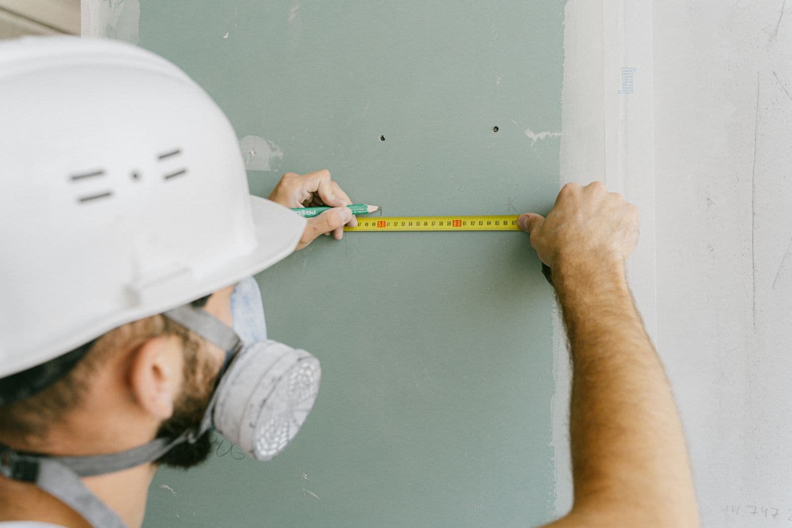 A craftsman measuring drywall before installation